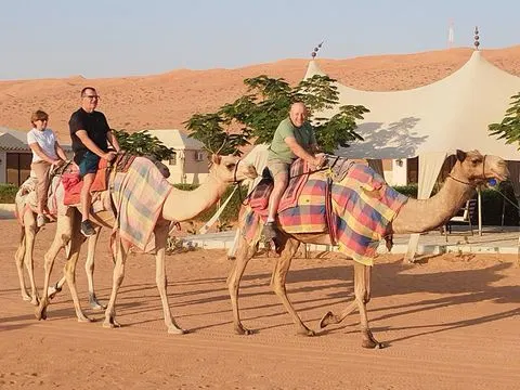 Relief de dunes dans un vaste paysage désertique, avec des personnes visibles.