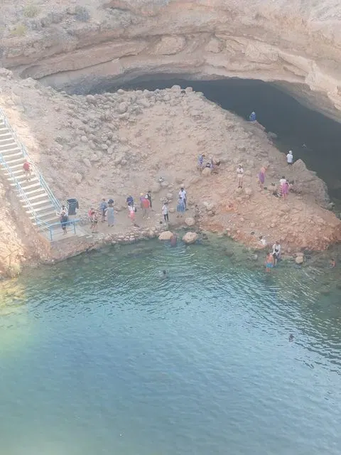 Canyon rocheux et bassin d’eau naturelle, avec des personnes visibles.