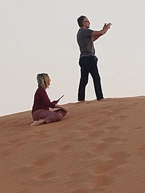 Relief de dunes dans un vaste paysage désertique, avec des personnes visibles.