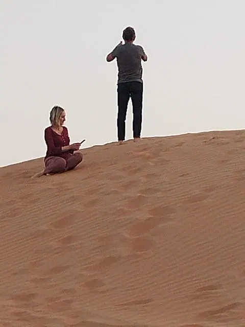 Relief de dunes dans un vaste paysage désertique, avec des personnes visibles.
