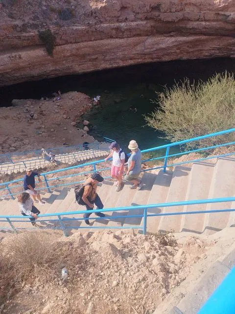 Canyon rocheux et bassin d’eau naturelle, avec des personnes visibles.