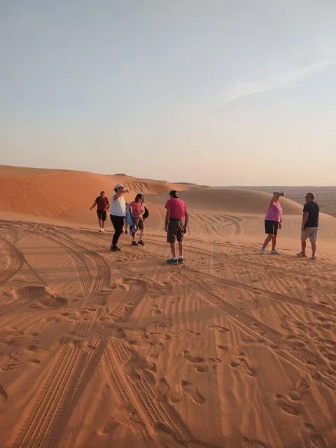 Relief de dunes dans un vaste paysage désertique, avec des personnes visibles.