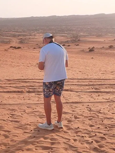 Relief de dunes dans un vaste paysage désertique, avec des personnes visibles.