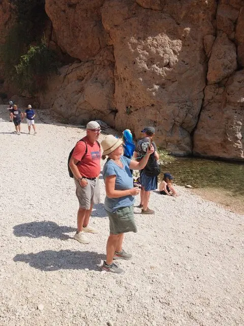 Canyon rocheux et bassin d’eau naturelle, avec des personnes visibles.