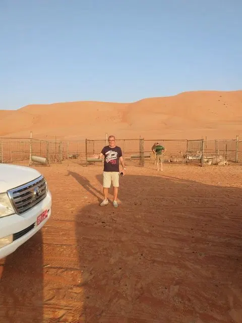 Relief de dunes dans un vaste paysage désertique, avec des personnes visibles.