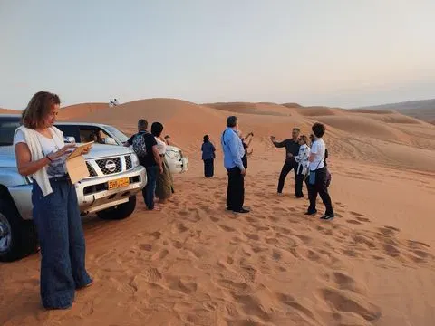Relief de dunes dans un vaste paysage désertique, avec des personnes visibles.