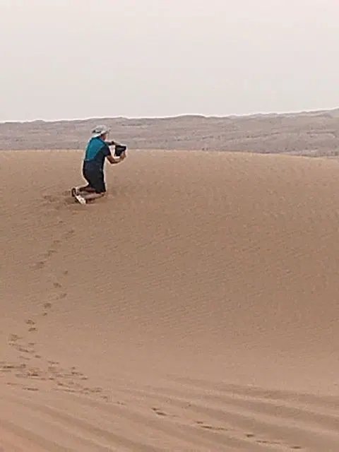 Relief de dunes dans un vaste paysage désertique, avec des personnes visibles.