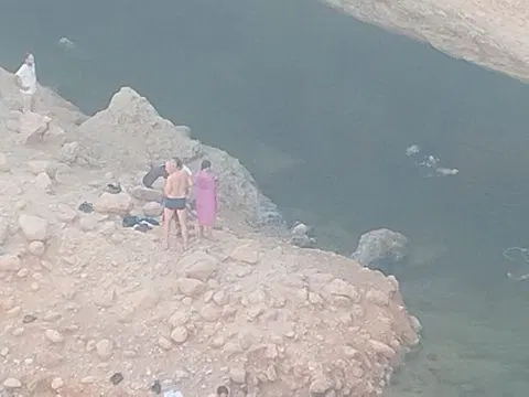 Canyon rocheux et bassin d’eau naturelle, avec des personnes visibles.