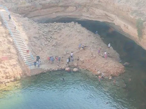 Canyon rocheux et bassin d’eau naturelle, avec des personnes visibles.