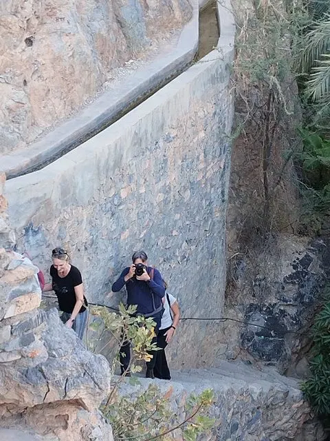Canyon rocheux et bassin d’eau naturelle, avec des personnes visibles.