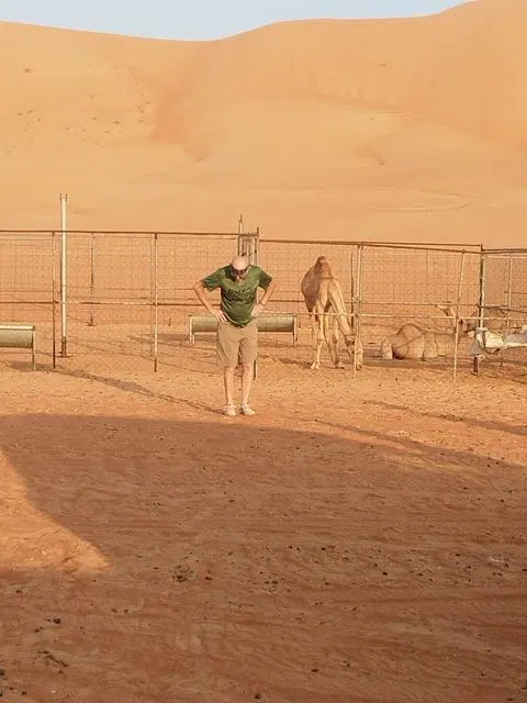 Relief de dunes dans un vaste paysage désertique, avec des personnes visibles.