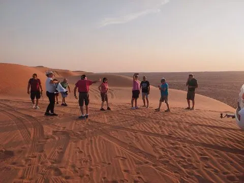 Relief de dunes dans un vaste paysage désertique, avec des personnes visibles.