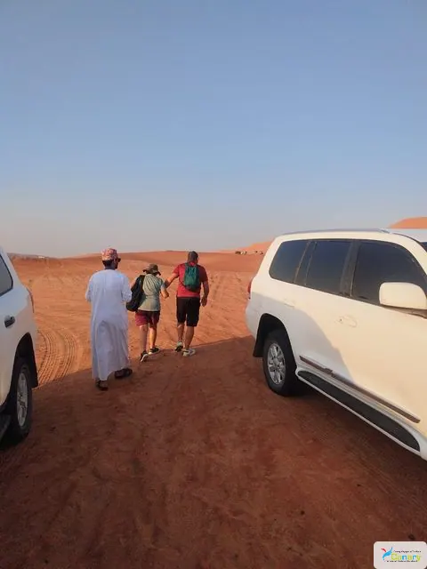 Relief de dunes dans un vaste paysage désertique, avec des personnes visibles.