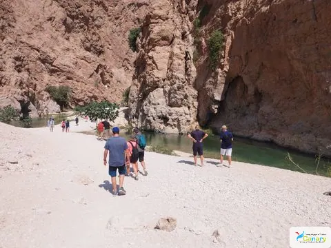 Canyon rocheux et bassin d’eau naturelle, avec des personnes visibles.
